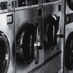 Black and white image of industrial washing machines in a retro style laundry facility.